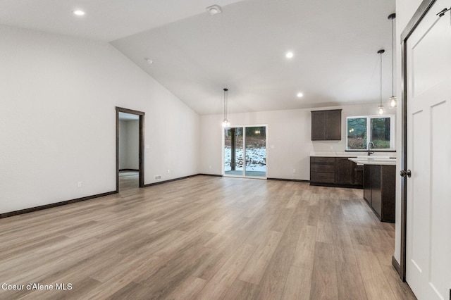 unfurnished living room with plenty of natural light, high vaulted ceiling, and light hardwood / wood-style floors