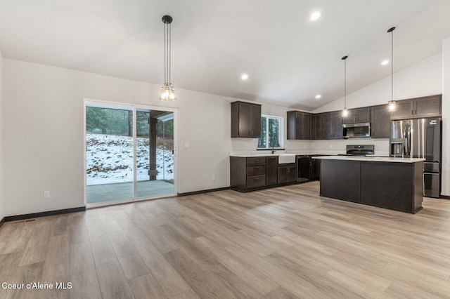 kitchen with decorative light fixtures, a center island, stainless steel appliances, and light hardwood / wood-style floors