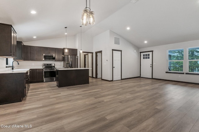 kitchen with a center island, high vaulted ceiling, hanging light fixtures, light wood-type flooring, and stainless steel appliances