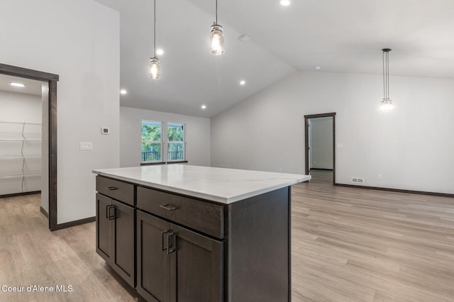 kitchen with light wood-type flooring, decorative light fixtures, vaulted ceiling, and a kitchen island