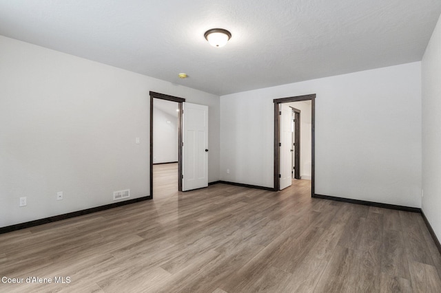 unfurnished room with wood-type flooring and a textured ceiling