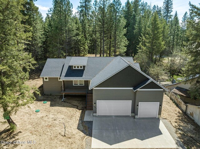 view of front facade with an attached garage, concrete driveway, and a forest view