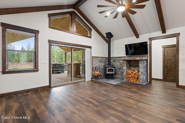 unfurnished living room with ceiling fan, beam ceiling, a wood stove, and dark wood-type flooring