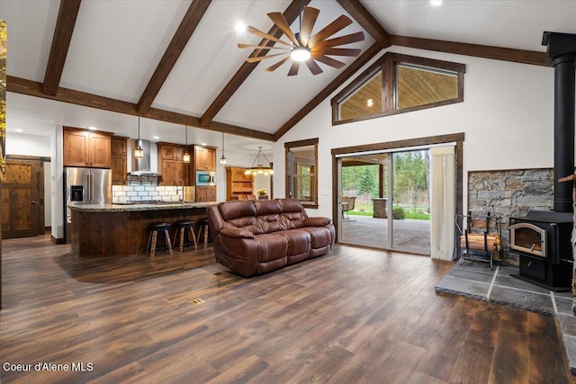 living room with ceiling fan, dark wood-type flooring, high vaulted ceiling, beamed ceiling, and a wood stove