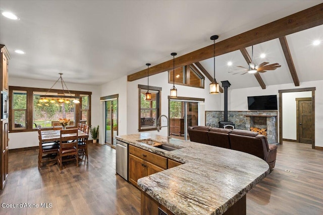 kitchen with lofted ceiling with beams, sink, hanging light fixtures, an island with sink, and stainless steel appliances