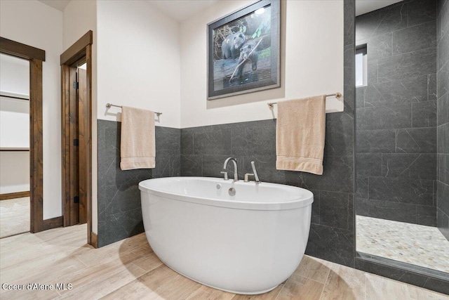 bathroom with separate shower and tub and tile walls