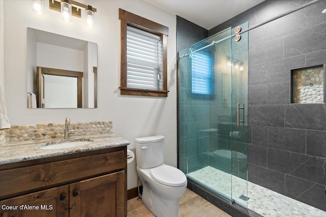 bathroom with vanity, a shower with shower door, and toilet