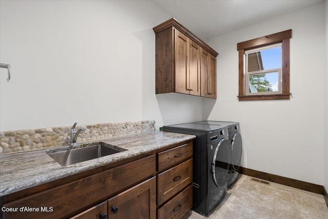 laundry room with cabinets, light tile patterned flooring, washing machine and dryer, and sink