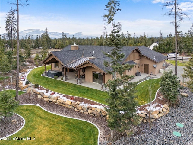 back of house with a patio area, a mountain view, and a yard