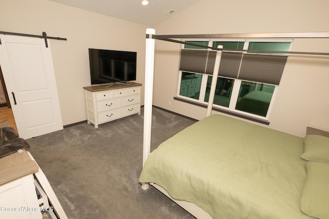 bedroom with dark colored carpet, a barn door, and vaulted ceiling