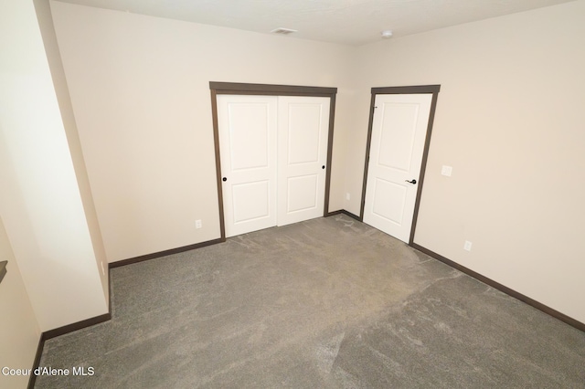 unfurnished bedroom with dark carpet and a closet