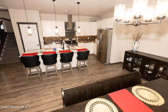 kitchen with decorative light fixtures, white cabinetry, a kitchen island with sink, and appliances with stainless steel finishes