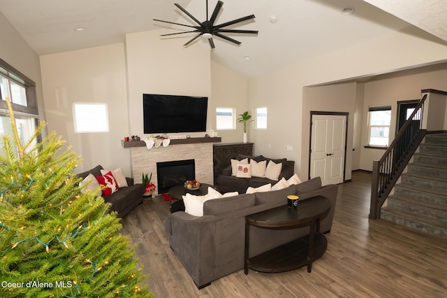 living room featuring dark hardwood / wood-style floors, ceiling fan, high vaulted ceiling, and a tiled fireplace