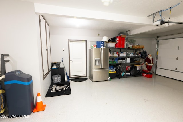 garage with stainless steel refrigerator with ice dispenser and a garage door opener