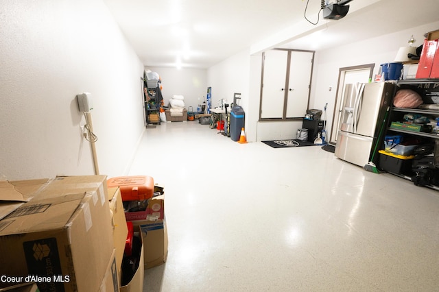 garage with stainless steel fridge and a garage door opener