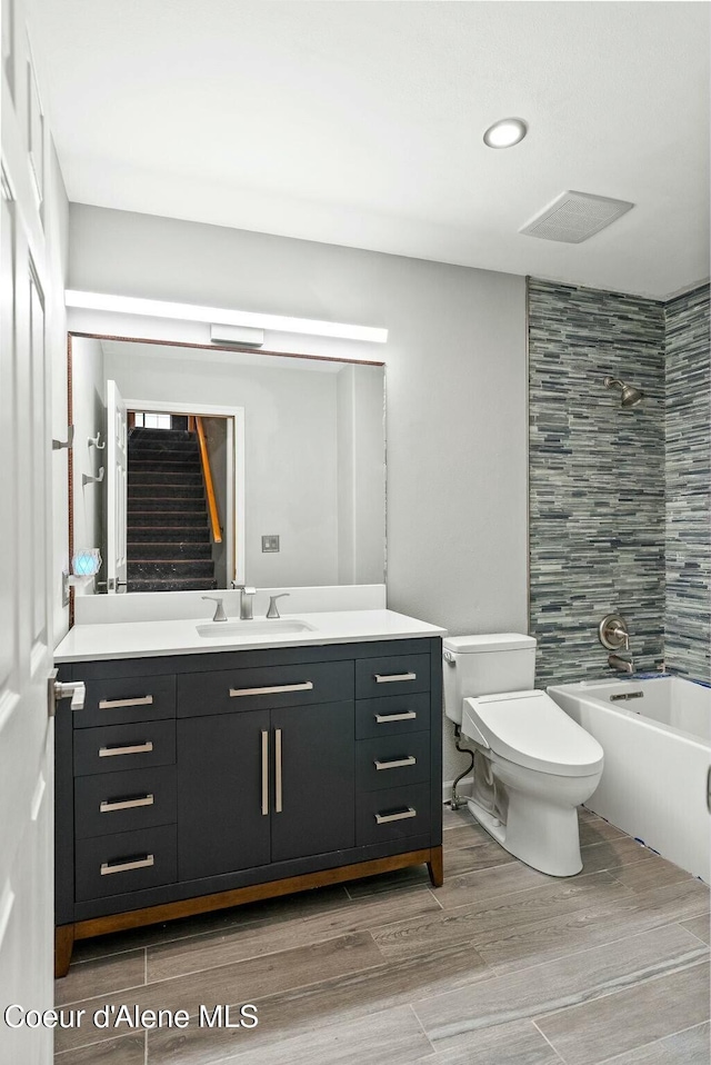 full bathroom with tiled shower / bath, vanity, and toilet