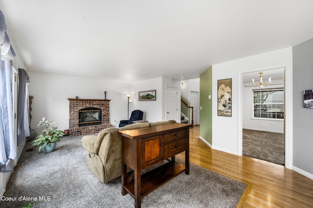 living room with a fireplace, wood-type flooring, and an inviting chandelier