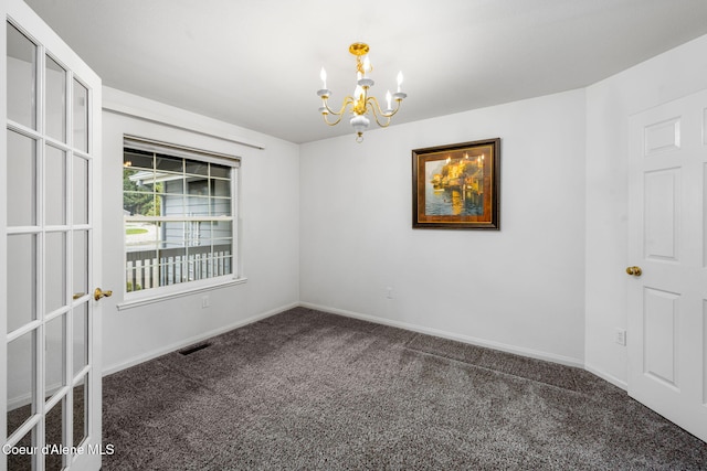 empty room with a notable chandelier and dark carpet