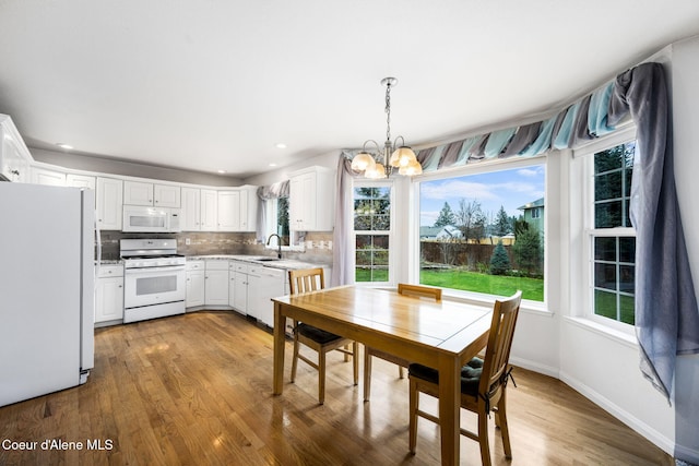 unfurnished dining area with an inviting chandelier, sink, and light hardwood / wood-style flooring