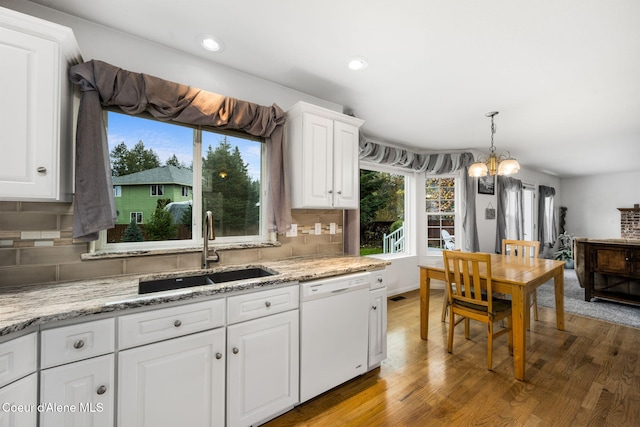 kitchen with hardwood / wood-style floors, dishwasher, white cabinets, sink, and tasteful backsplash