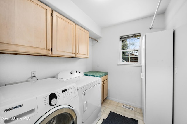 washroom featuring washing machine and clothes dryer and cabinets