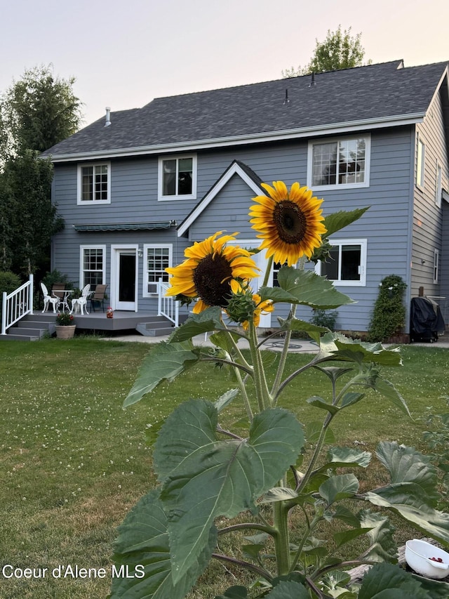 back house at dusk featuring a deck and a yard