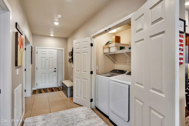 laundry area with independent washer and dryer and light tile patterned floors