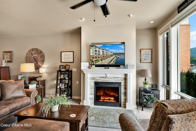 living room featuring a stone fireplace and ceiling fan