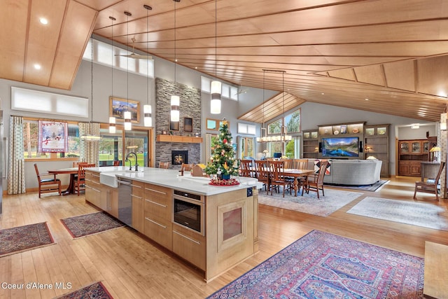 kitchen with sink, stainless steel appliances, a towering ceiling, an island with sink, and wood ceiling