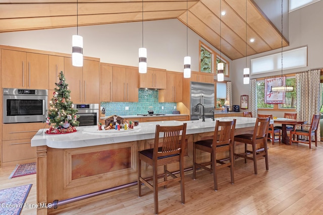 kitchen with a spacious island, decorative backsplash, high vaulted ceiling, and stainless steel appliances