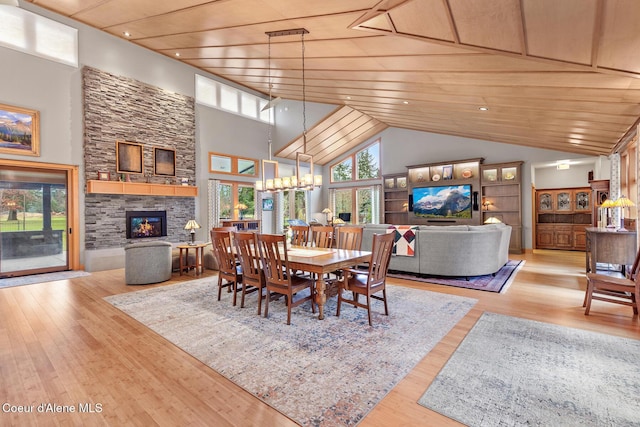 dining space with a stone fireplace, wooden ceiling, a high ceiling, and light wood-type flooring