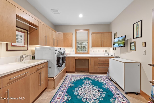 washroom with washer and dryer, cabinets, and sink