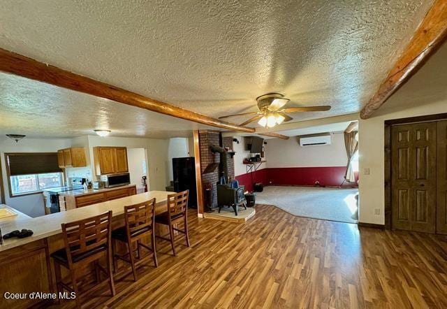 dining area with an AC wall unit, a wood stove, ceiling fan, and a textured ceiling