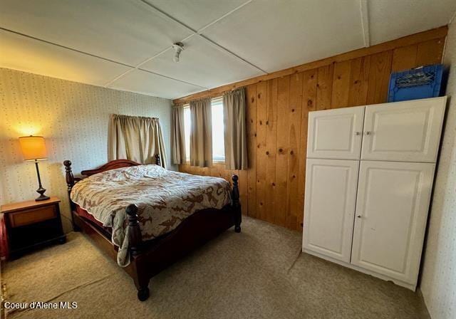 bedroom with light colored carpet and wooden walls