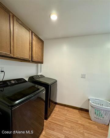 washroom with cabinets, light wood-type flooring, and washing machine and clothes dryer