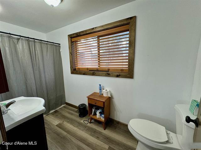 bathroom featuring hardwood / wood-style flooring, vanity, toilet, and walk in shower