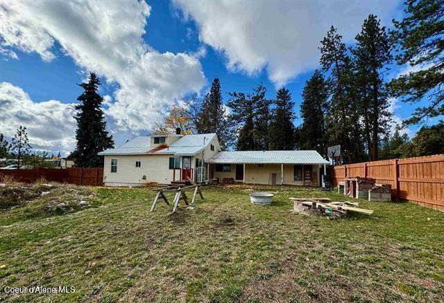 back of property with solar panels and a lawn