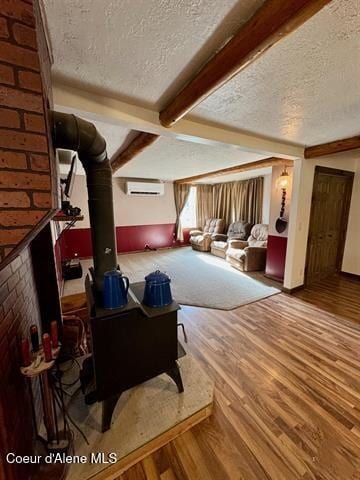 interior space featuring beamed ceiling, a textured ceiling, hardwood / wood-style flooring, and a wall mounted AC