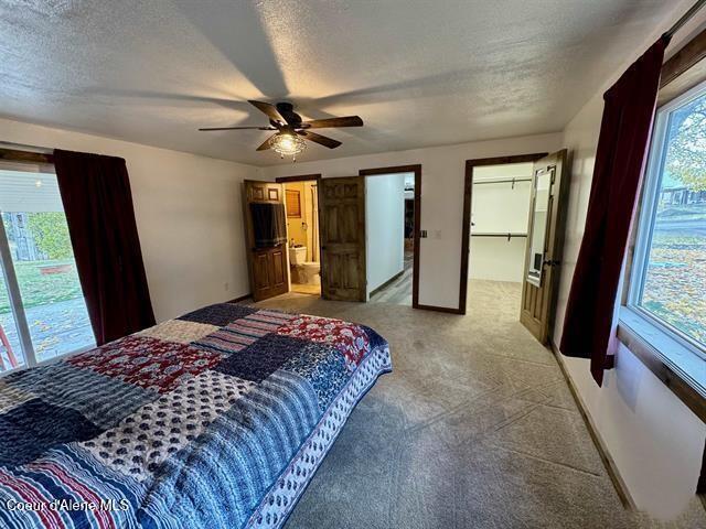 bedroom with carpet flooring, ceiling fan, a spacious closet, and a textured ceiling