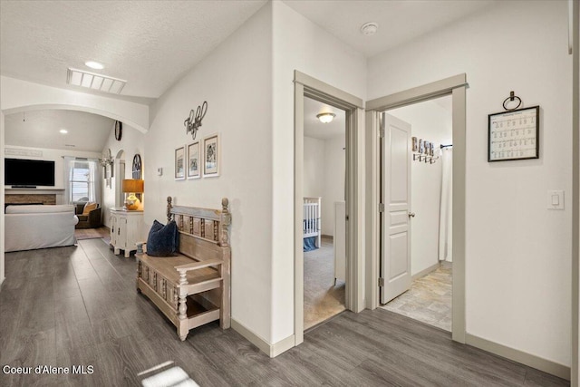 hallway featuring hardwood / wood-style floors, a textured ceiling, and vaulted ceiling