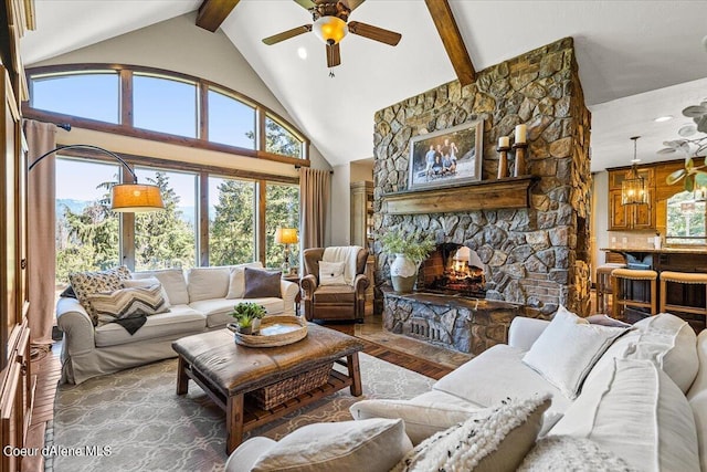 living room with a stone fireplace, a wealth of natural light, beamed ceiling, and hardwood / wood-style flooring