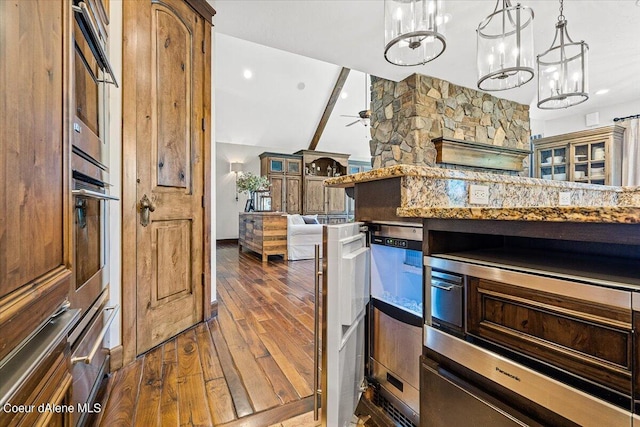 kitchen with vaulted ceiling, hanging light fixtures, dark wood-type flooring, and ceiling fan with notable chandelier