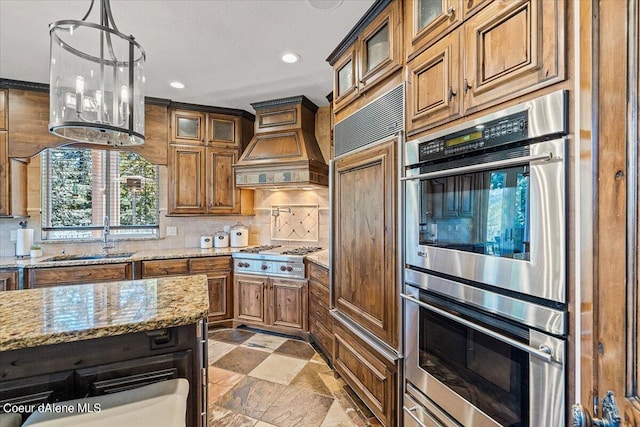 kitchen with premium range hood, sink, decorative backsplash, appliances with stainless steel finishes, and light stone counters