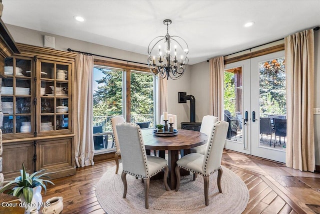 dining area with dark hardwood / wood-style flooring, a wood stove, a healthy amount of sunlight, and a notable chandelier