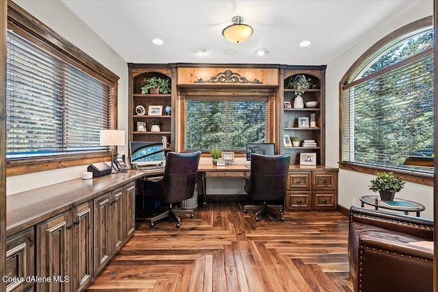 office area featuring a healthy amount of sunlight, dark parquet floors, and built in desk