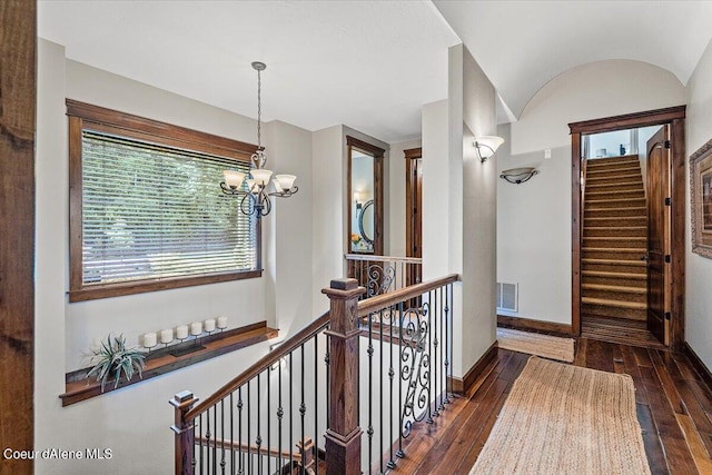 hall featuring dark hardwood / wood-style floors, vaulted ceiling, and a notable chandelier