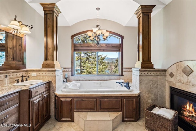 bathroom with a washtub, an inviting chandelier, decorative columns, tile patterned floors, and vanity