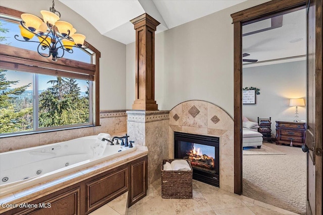 bathroom featuring lofted ceiling, a relaxing tiled tub, ornate columns, a fireplace, and a chandelier