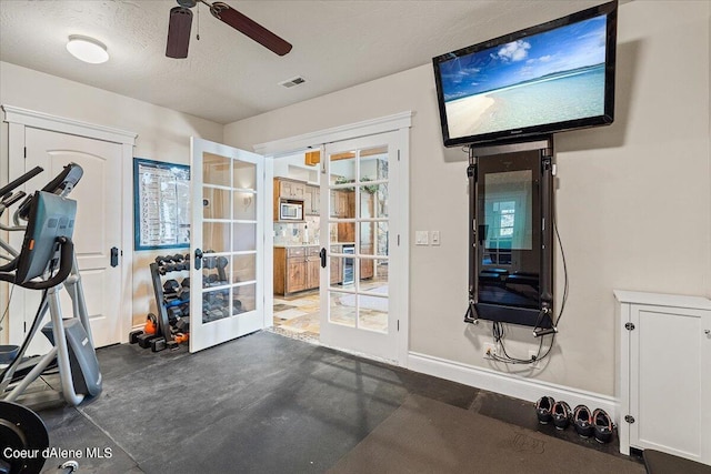 workout area featuring ceiling fan, french doors, and a textured ceiling