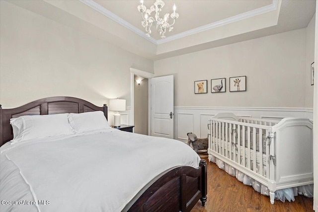 bedroom featuring a raised ceiling, dark hardwood / wood-style flooring, a chandelier, and ornamental molding